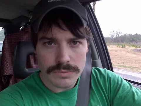 selfie of man with mustache in car